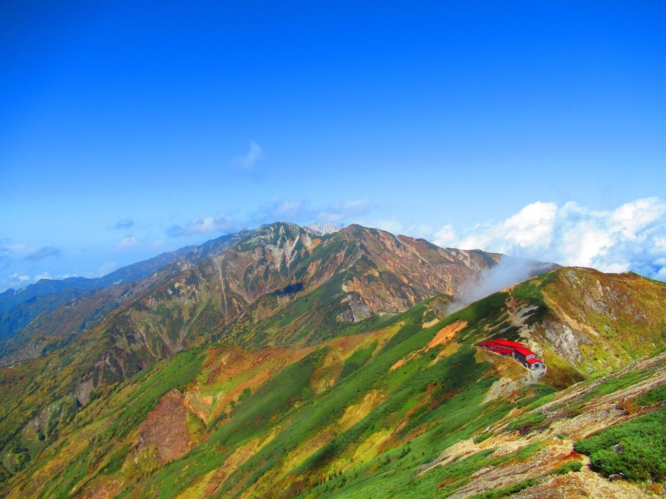 「雲の切れ間に...」五竜岳から見る唐松岳(手前)、白く見えるのは白馬三山(奥)